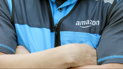 A close-up shot of an Amazon employee's shirt as he stands with his arms crossed