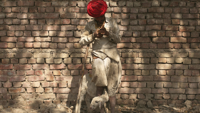 A shepherd looks at his mobile phone in India.