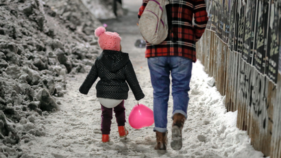 child walking in snow with adult