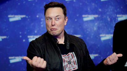 Elon Musk grimaces and gestures with two thumbs