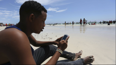 A Somali man browses the internet on his mobile phone at a beach along the Indian Ocean coastline in Somalia's capital Mogadishu, January 10, 2014.
