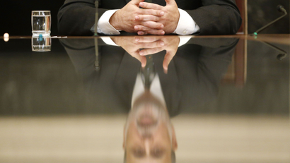 U.S. Federal Reserve Chairman Ben Bernanke is reflected in a glass table top as he holds town hall event for teachers at the Federal Reserve Board's building in Washington November 13, 2013.