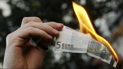 A demonstrator burns a five euro note during a protest in downtown Madrid against capitalism.