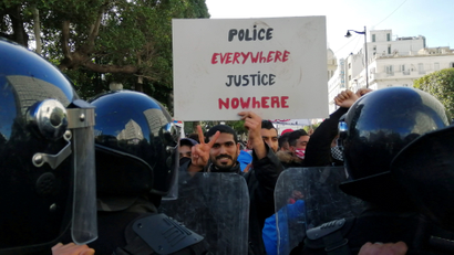 Police officers stand guard as a demonstrator carries a placard during an anti-government protest in Tunis, Tunisia on Jan. 23.