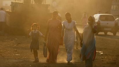 People walk through haze at an industrial area in Mumbai December 3, 2009. India will not accept a legally binding emission cut nor a peak year of carbon emissions at the global climate talks in Copenhagen, Environment Minister Jairam Ramesh said on Thursday. REUTERS/Arko Datta