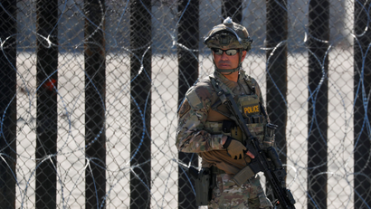 An armed U.S. Customs and Border Patrol agent stands watch at the border fence next to the beach in Tijuana, at the Border State Park in San Diego, California