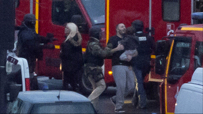 A security officer directs released hostages after they stormed a kosher market to end a hostage situation, Paris, Friday, Jan. 9, 2015. Explosions and gunshots were heard as police forces stormed a kosher grocery in Paris where a gunman was holding at least five people hostage. (AP Photo/Michel Euler)