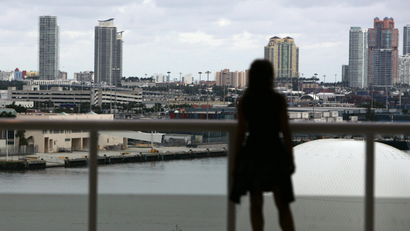 A woman stands on the balcony overlooking the offices of downtown Miami.
