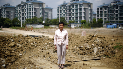 Xu Haifeng poses at a construction site area where her house stood in Wuxi, Jiangsu province, August 20, 2013. When Xu's home was razed three years ago, she went to China's capital Beijing to complain about the city and county governments that ordered the demolition. Since then she says family members have been kidnapped at least 18 times, typically having black bags thrust over their heads before being taken to a hotel-turned-illegal jail in the eastern city of Wuxi and locked for weeks in a tiny, windowless room. Xu's story is shocking even in a country that has become used to tales of arbitrary and sometimes violent land expropriations. It illustrates how the stresses from the deep indebtedness of China's local governments extend beyond banks into the lives of ordinary Chinese, as hard-up authorities resort to any means they can in a desperate scramble for funds. Picture taken August 20, 2013. REUTERS/Carlos Barria