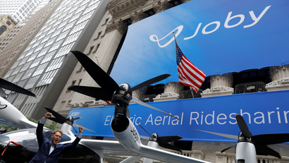 Joby Aviation founder JoeBen Bevirt pumps his fist next to a large air taxi drone parked in front of the New York Stock Exchange.