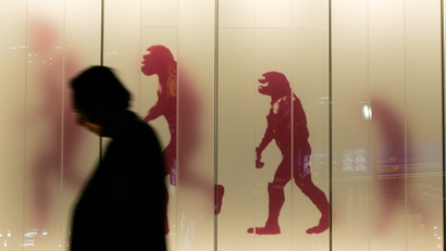 A man walks past a sign showing the evolution of man in a business district in downtown Tokyo November 17, 2008.