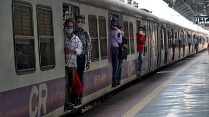 Commuters wearing protective face masks travel in a suburban train in Mumbai