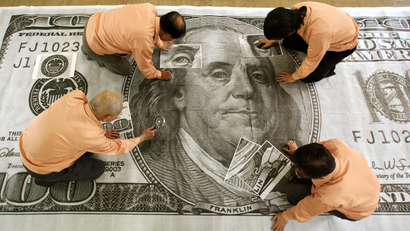 People examine a giant $100 bill featuring Benjamin Franklin