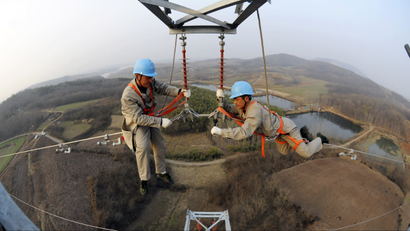 Workers check on electricity pylon situated amid farmlands in Chuzhou, Anhui province, February 5, 2013. A leading think tank of China predicted that China's GDP will grow in 2013 at a rate of 8.4 percent, up by 0.6 percentage points from that of 2012, Xinhua News Agency reported. REUTERS/China Daily