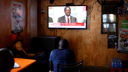 Men watch a television set as opposition leader Raila Odinga addresses the nation during a press conference, at the Mathare slum, in Nairobi, Kenya August 16, 2017.
