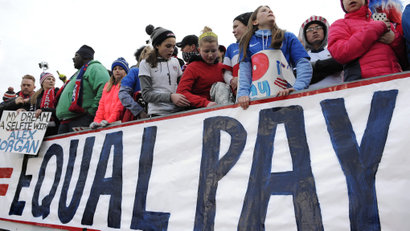 FILE - In this April 6, 2016, file photo, fans stand behind a large sign for equal pay for the women's soccer team during an international friendly soccer match between the United States and Colombia at Pratt &amp; Whitney Stadium at Rentschler Field in East Hartford, Conn. The World Economic Forum's annual Global Gender Gap Report released on Oct. 25, 2016, found that the global gender pay gap will not be closed for another 170 years if current trends continue. (AP Photo/Jessica Hill, File)