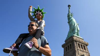 A girl mimics the Statue of Liberty as she poses for photos in front of the landmark ahead of the Independence Day holiday in New York July 3, 2015.