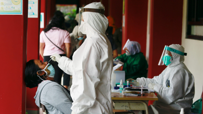 A healthcare worker in personal protective equipment takes a swab sample from a person to test for the coronavirus disease (COVID-19) during mass testing at a school in Jakarta, Indonesia, July 2, 2021. REUTERS/Ajeng Dinar Ulfiana