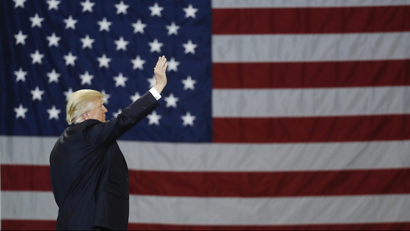 Trump waving in front of flag