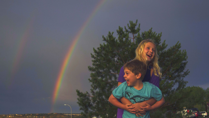 Children playing under a rainbow