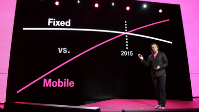 T-Mobile CEO John Legere speaks in front of a chart showing the relation of traditional fixed phone lines vs mobile phone lines at T-Mobile's Uncarrier 5.0 event, Wednesday, June 18, 2014, in Seattle. (AP Photo/Ted S. Warren)