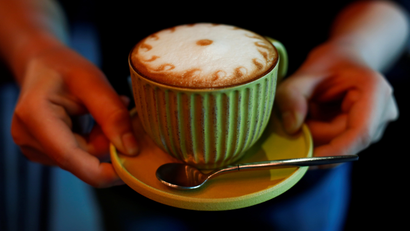 A barista holds a cappuccino coffee at the La Tercera cafe in Beijing