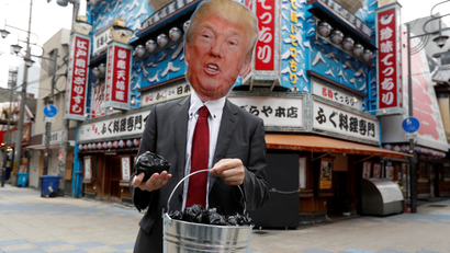 A protester wearing the mask of U.S. President Donald Trump carries a bucket of coal