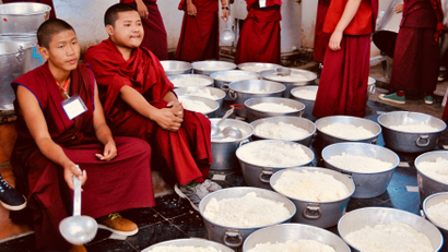Buddhist monks serve food at monastery.