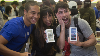 Alejandro de Rosa (R) and Melisa Racineti of Buenos Aires, Argentina pose with their new Apple iPhone 5s phones with Apple employee Jay at the Apple Retail Store on Fifth Avenue in Manhattan, New York September 20, 2013. Apple Inc's newest smartphone models hit stores on Friday in many countries across the world, including Australia and China. REUTERS/Adrees Latif