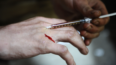 A man injects heroin into a vein in his hand at an abandoned house in Ljubljana