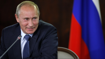 Vladimir Putin smiles while chairing a meeting in Moscow.
