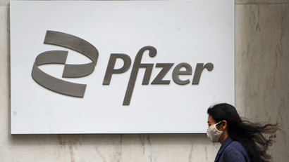 A person walks past a Pfizer logo in New York City