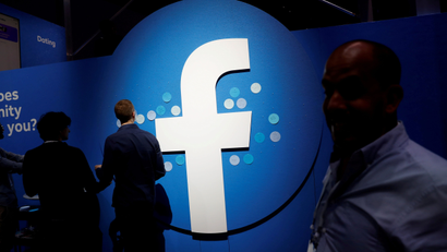 Attendees walk past Facebook logo at a conference