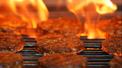 Burgers are cooked over a flame on a grill