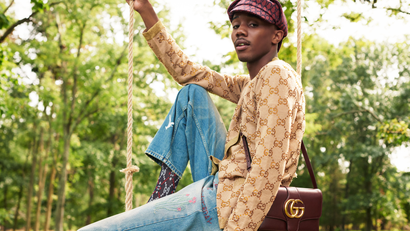 A male model decked out in Gucci sits casually on a swing