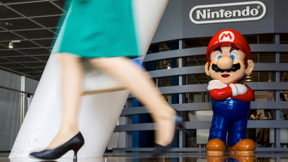 Woman walks past figure of "Mario" video game character at Nintendo centre in Tokyo