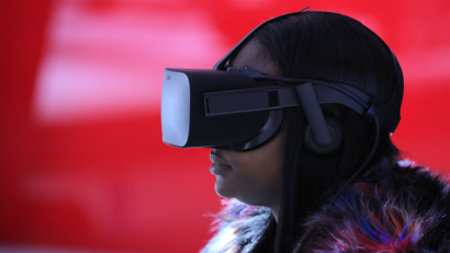 A woman wears VR goggles as she sits in a virtual reality booth.