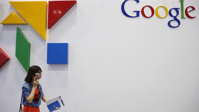 A woman walks past a logo of Google .