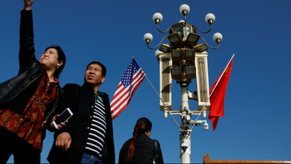 People pass under a pole with security cameras, U.S. and China's flags near the Forbidden City ahead of the visit by U.S. President Donald Trump to Beijing, China November 8, 2017.