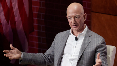 Jeff Bezos gesticulating a point with outstretched arms during a speech