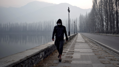 A man wearing a protective face mask walks along the banks of Dal Lake on a cold morning in Srinagar