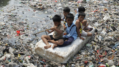 Children sitting on a makeshift raft play in a river full of rubbish in a slum area of Jakarta September 19, 2012. REUTERS/Enny Nurahen