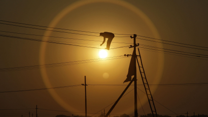 An employee from the electricity board works on newly installed overhead power cables ahead of the "Kumbh Mela", or Pitcher Festival, as the sun sets in the northern Indian city of Allahabad December 7, 2012. REUTERS/Jitendra Prakash (INDIA - Tags: ENERGY BUSINESS EMPLOYMENT TPX IMAGES OF THE DAY)