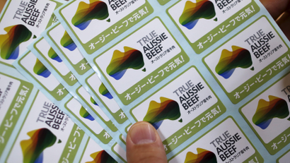 A man holds campaign stickers to promote selling beef meat imported from Australia at a supermarket in Tokyo, Japan, November 16, 2015.