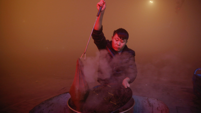 A man cooks in open air as heavy smog blankets Shengfang, in Hebei province, on an extremely polluted day with red alert issued, China December 19, 2016. REUTERS/Damir Sagolj - RTX2VONI
