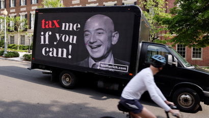 A black truck with a photo of Jeff Bezos reads "tax me if you can!"