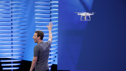 Facebook CEO Mark Zuckerberg points to a drone flying behind him during his keynote address at the F8 Facebook Developer Conference Tuesday, April 12, 2016, in San Francisco. Facebook says people who use its Messenger chat service will soon be able to order flowers, request news articles and talk with businesses by sending them direct text messages. At its annual conference for software developers, Zuckerberg said the company is releasing new tools that businesses can use to build "chat bots," or programs that talk to customers in conversational language. (AP Photo/Eric Risberg)