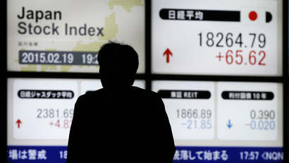 A man walks past an electronic board showing Japan's Nikkei average (top R) outside a brokerage in Tokyo February 19, 2015. Japanese stocks rose to a 15-year high on Thursday, helped by gains in financial stocks, while Sony Corp jumped on a well-received business plan. REUTERS/Toru Hanai (JAPAN - Tags: BUSINESS)
