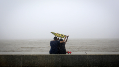 A couple tries to hold on to an umbrella flipped inside out at a sea front, in Mumbai