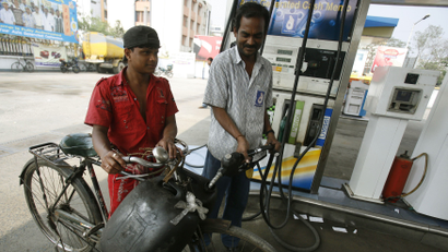 A worker fills plastic containers with petrol at a pump in Kolkata